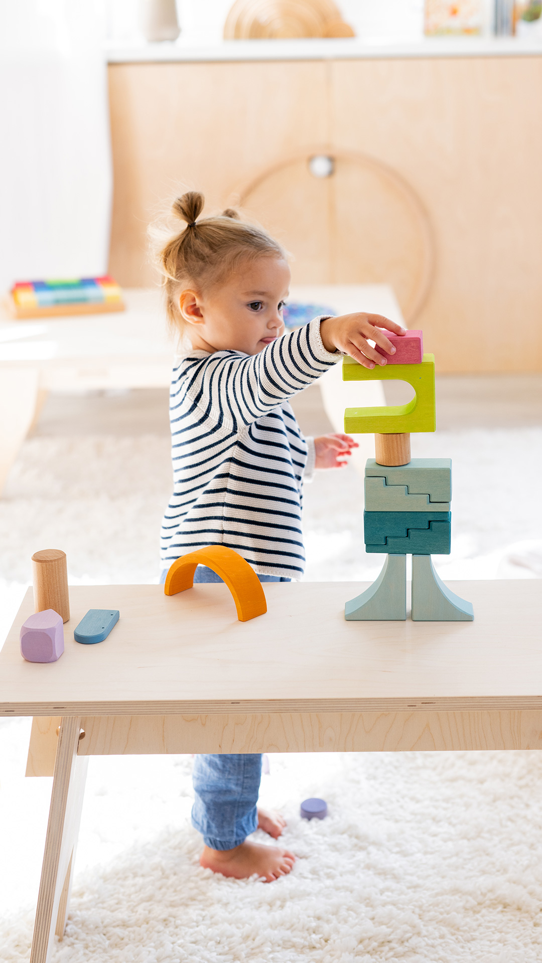 Little girl building a fantasy figure out of wooden building blocks.