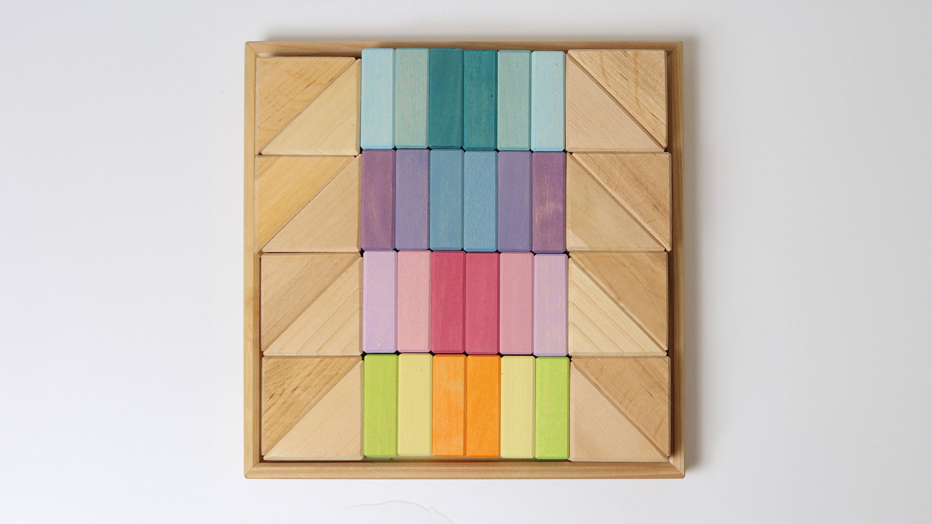 Wooden frame with pastel-coloured and natural-coloured building blocks in triangle and rectangle shapes.
