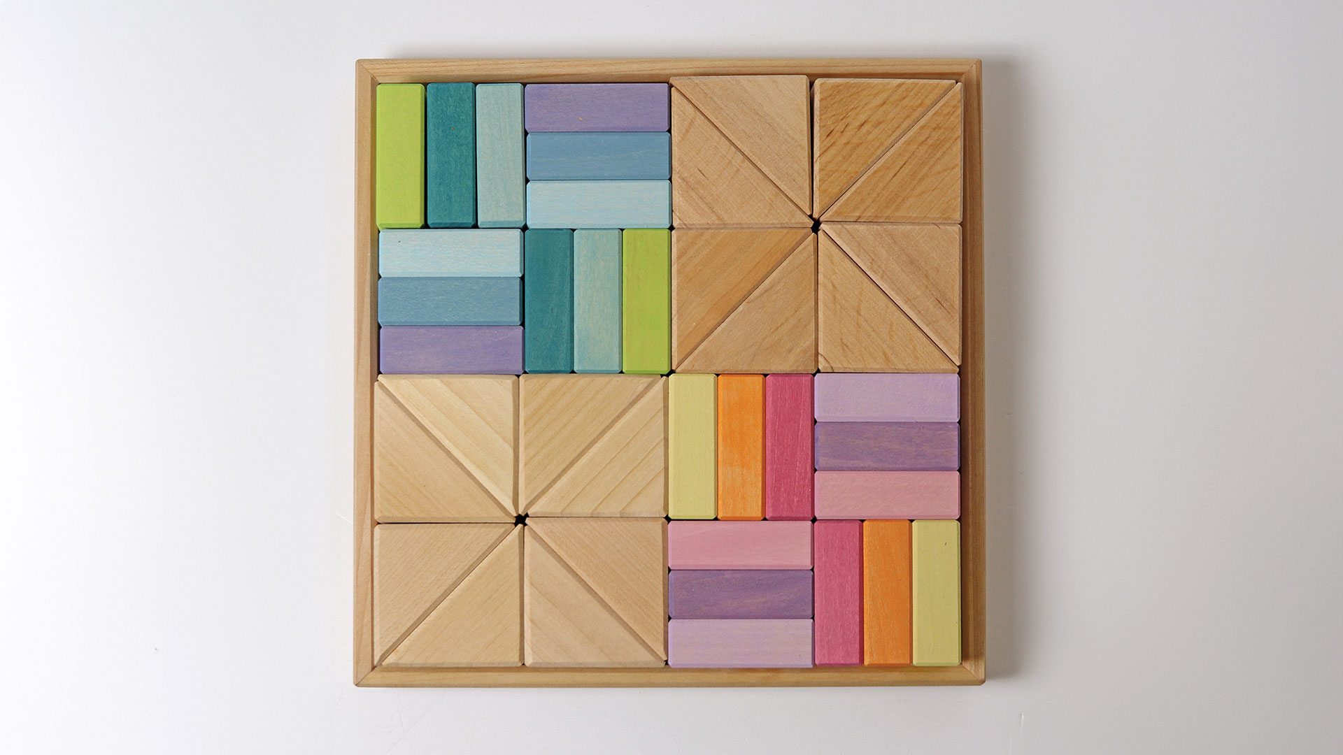 Wooden frame with pastel-coloured and natural-coloured building blocks in triangle and rectangle shapes.