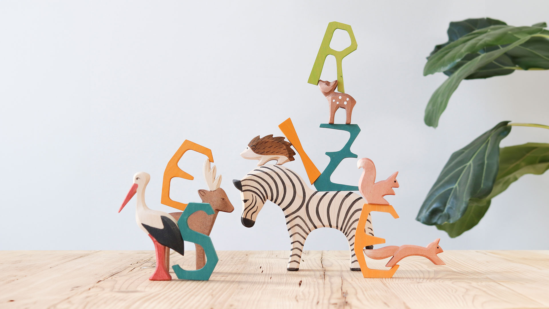 Tierfiguren (Zebra, Storch, Elch) und Holzbuchstaben (Z, S, E) stehen auf einem Tisch